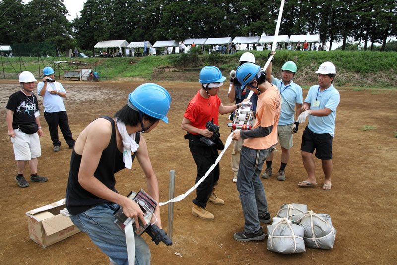 クライマーを取り付ける神奈川大学工学部のメンバー。参加者も運営スタッフも取材陣も全員ヘルメット着用