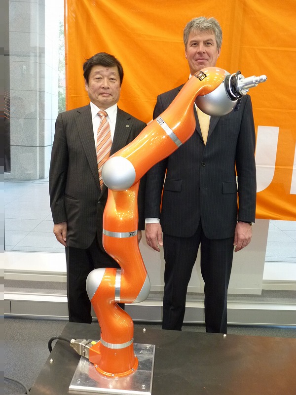 KUKAロボティクスジャパンの安藤晃二代表取締役社長(左)とドイツKUKA Roboterのマンフレッド・グンデルCEO(右)。手前は最新の「Light Weight Robot」(LWR)