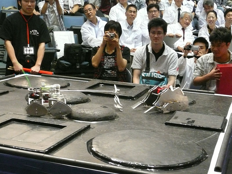 【写真27】大阪工業大学機械工学研究部の「EV」(写真右)。外観にもこだわりを見せるマシンだ。アームの位置が最下点にくると、あたかも動物のサイのようなフォルムになるように設計したという。「TMCシステム賞」を受賞