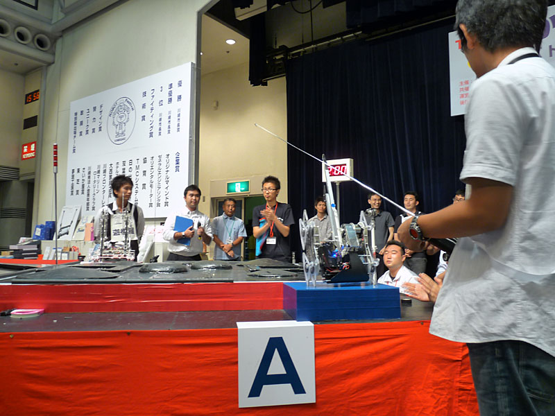【写真38】ブロック1の代表決定戦。大阪工業大学機械工学研究部「迦楼羅」と立命館大学ロボット技術研究会OB「FUN」の戦い。勝負の前に両者の意気込みを聞いているところ