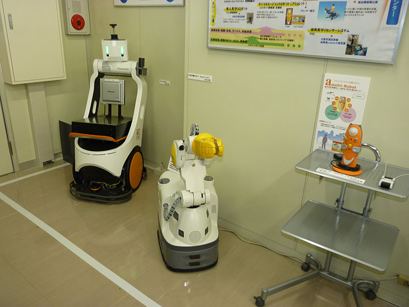 荷物を運ぶポーターロボット(左)と生産支援ロボット「ソシオ」(中)、行き先をガイドし見守るモバイルエージェント「アミュレットロボット」(右)