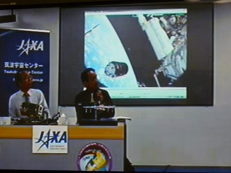 記者会見に出席する虎野吉彦HTVプロジェクトマネージャ(左)と山中浩二フライトディレクタ(右)。JAXA筑波宇宙センターからの中継映像より